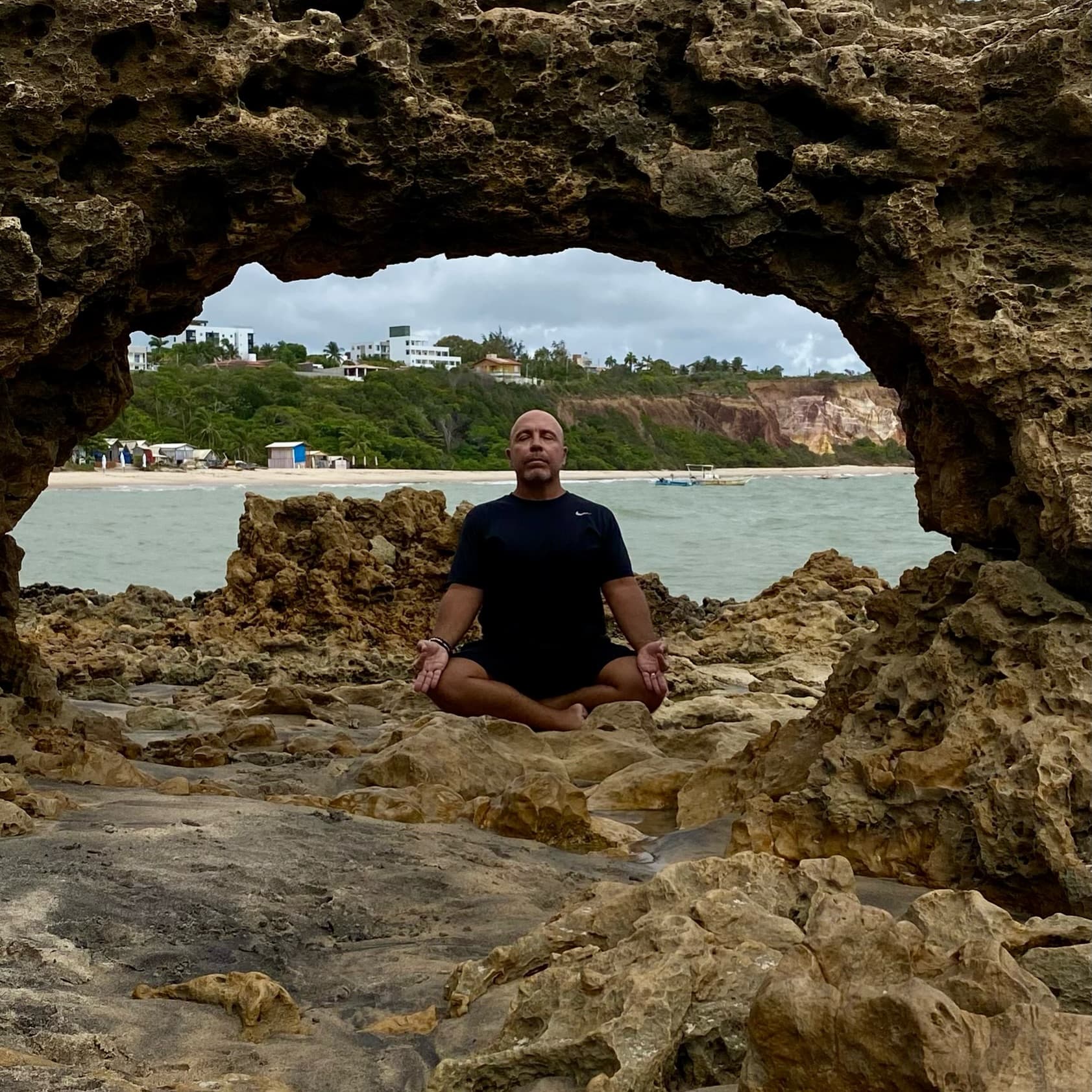 Artur França meditando à beira-mar, na Paraíba